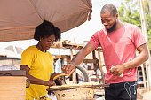 afrikanischer-mann-kauft-gebratene-kochbanane-von-einer-frau-mit-gelbem-hemd-in-nigeria.jpg?b=1&s=170x170&k=20&c=SZE5srkBrf03O9XbR8vzsW0WSnikZKX_VxN1jqYHihg=
