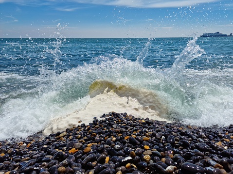 A strong wave of the sea breaking on the small stones of the shore