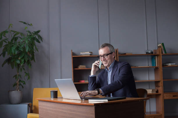 istock Laughing mature business man talking on phone 1460469496