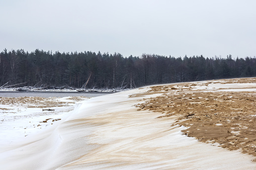 Sea sand with white snow, gray sky