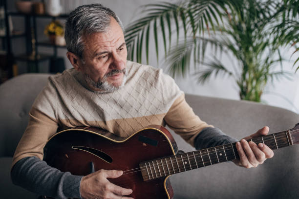 istock An elderly man is home alone, playing the guitar 1460473962
