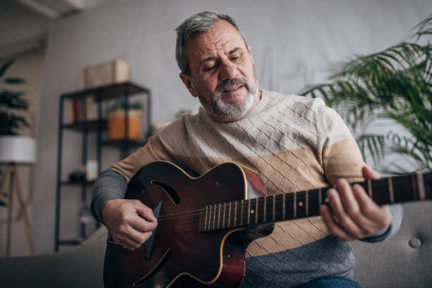 istock An elderly man is home alone, playing the guitar 1460474118