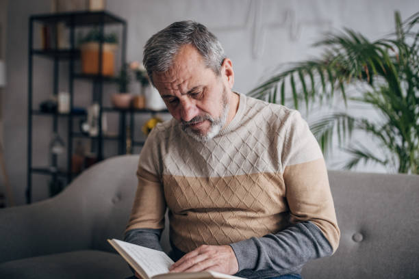 istock An elderly man is at home reading a book 1460474123