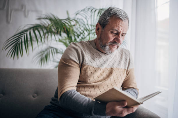 istock An elderly man is at home reading a book 1460474160
