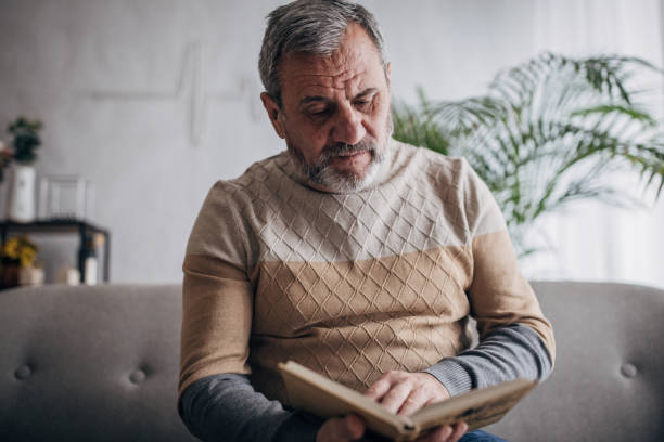 istock An elderly man is at home reading a book 1460474163