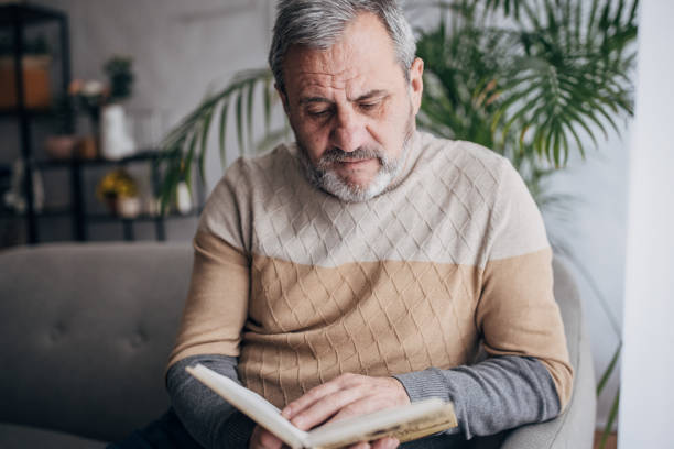 istock An elderly man is at home reading a book 1460474165