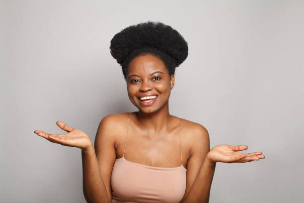 istock Cheerful brunette woman holding empty open palm hands and looking at camera against white studio wall banner background 1460477040