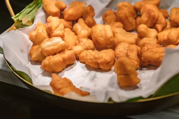 Photo of Deep-fried traditional Thai dough, deep-fried dough ready to serve for snack breakfast, warm light from above.