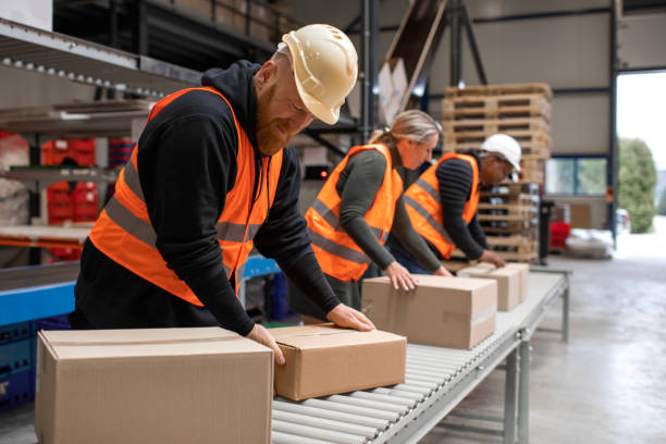Three warehouse workers on a packing and delivery production line stock photo