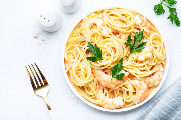 istock Spaghetti pasta with shrimp and parsley on plate on white table background. Top view, copy space 1460478991