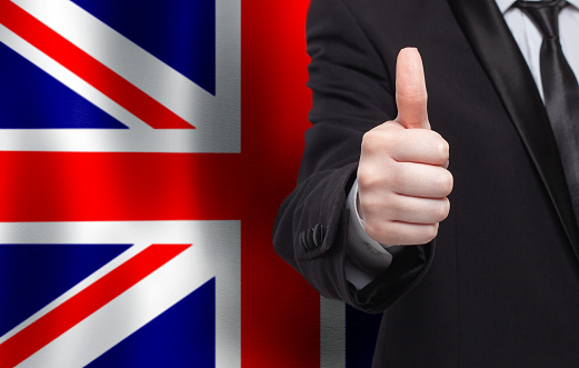 UK concept. Businessman showing thumb up on the background of flag of England