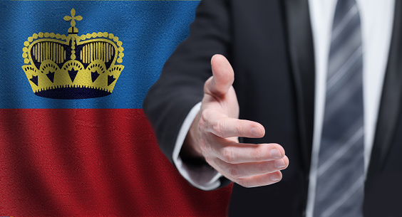 Business, politics, cooperation and travel in Principality of Liechtenstein concept. Hand on flag of Liechtenstein background.