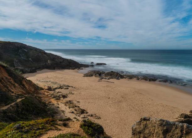 istock View of empty small sand beach with with long exposure blurred ocean waves and sharp rock and cllifs at wild Rota Vicentina coast near Porto Covo, Portugal. 1460487107