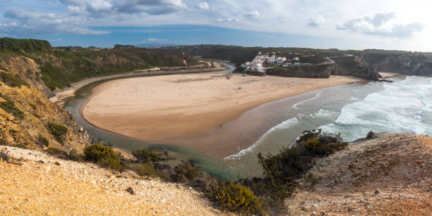 istock Panoramic view of Praia de Odeceixe Mar Surfer beach with golden sand, atlantic ocean waves, river bend and white houses of Odeceixe village. Rota Vicentina coast, Odemira, Portugal. 1460487708