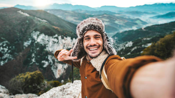 istock Handsome young man with hat and backpack taking selfie with smart mobile phone device outside - Hiker taking self portrait on the top of the mountain - Travel, sport, technology and life style concept 1460493461