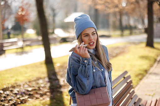 Smiling young woman talking on mobile phone in city park