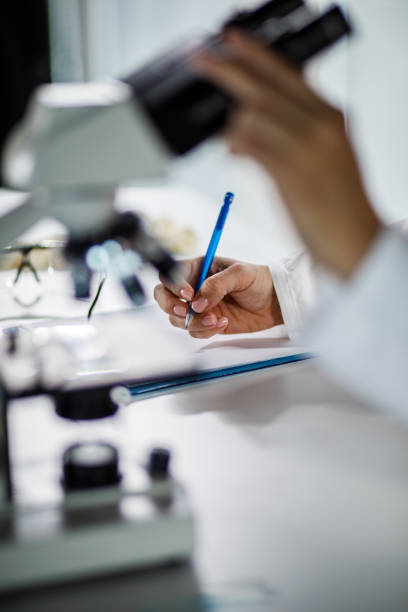 istock Cut out shot of female scientist writing notes on a clipboard after analyzing samples under a microscope 1460496544