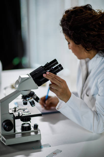 istock Cut out shot of female scientist writing notes on a clipboard after analyzing samples under a microscope 1460496554