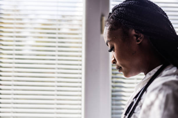 istock Overworked doctor taking a break from work by the window, looking outside, contemplating 1460498542