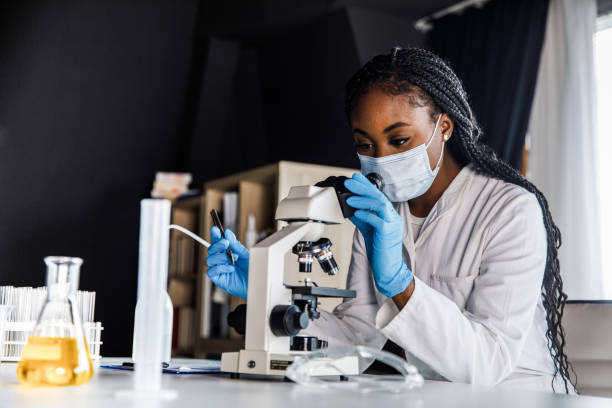 copia de la toma espacial de la científica femenina analizando una muestra bajo un microscopio mientras investiga - research medical student doctor clinic fotografías e imágenes de stock