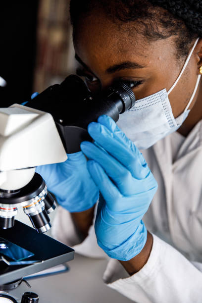 istock Headshot of female scientist looking through the microscope and analyzing a sample 1460498906