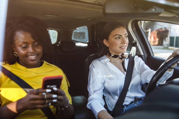 istock Young woman driving while her friend is looking up direction on a map via smart phone passenger seat 1460501113