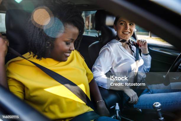 Two Girlfriends Sitting In A Car And Fastening Their Seat Belts Before Going For A Drive Stock Photo - Download Image Now
