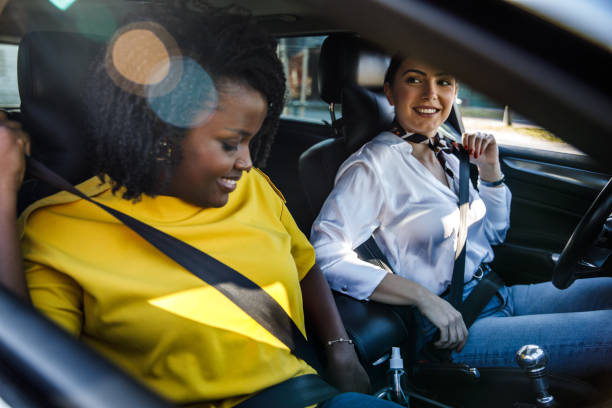 dwie dziewczyny siedzące w samochodzie i zapinające pasy bezpieczeństwa przed pójściem na przejażdżkę - spinal zdjęcia i obrazy z banku zdjęć