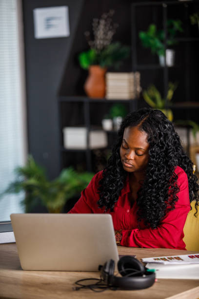 istock Young woman sitting at her desk in a modern office and using laptop 1460502392