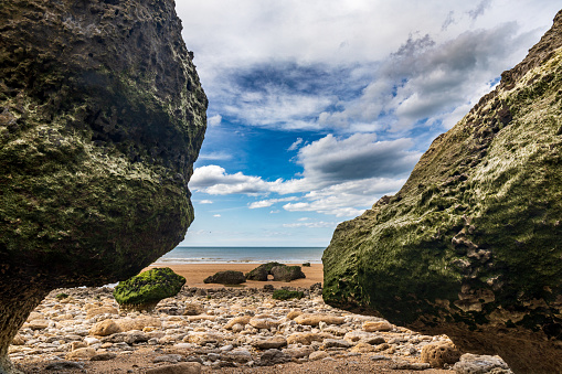 Villers-sur-mer, Normandy, France - Rocks on the beach at low tide near the black cows (vaches noires) cliff