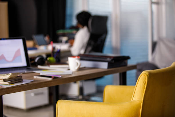 Selective focus shot of a messy desk with a graph on laptop screen in a co-working office space. Part of a series.