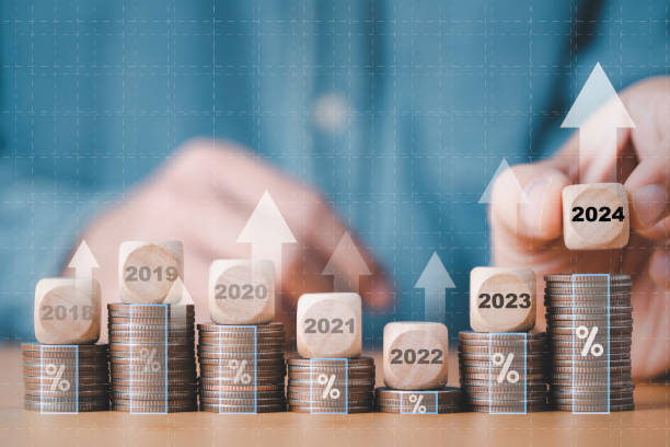 istock Businessman hand stacking wooden block cube 2024 on coins stacking for setup objective target business cost and budget planing of new year concept. 1460503718