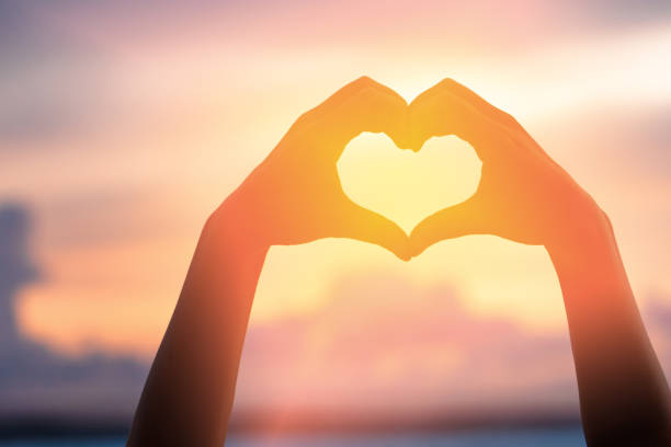 istock Hands forming a heart shape with sunset silhouette 1460503890