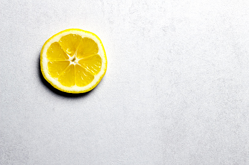 Lemon slice on white table. Copy space. Horizontal orientation. No people.