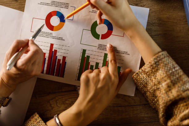 istock Two unrecognizable businesswomen reviewing graphs and charts on a document 1460506540