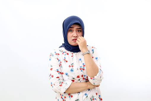 Worried asian muslim woman standing with scared face expression. Isolated on white background