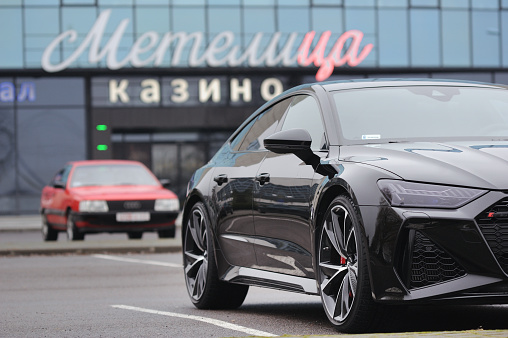 Belarus, Minsk - 24.01.2023: Black premium car Audi RS 7 Sportback and Audi 100 are parked on the city street. Audi RS7 Sportback.