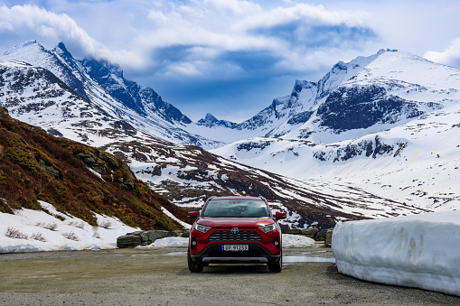 Toyota SUV parked in front of snowcapped mountain ranges at Nedre Oscarshaug Viewpoint, Jotunheimen National Park, Norway
