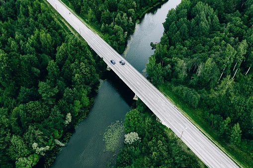 Aerial view of road over the blue river and green woods in summer Finland