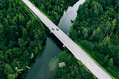 Aerial view of road over the blue river and green woods in Finland