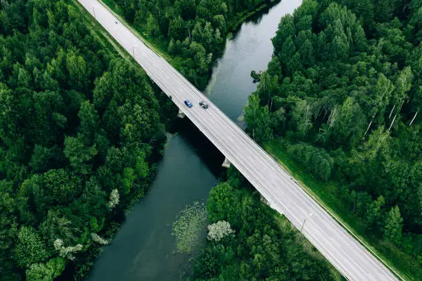 Photo of Aerial view of road over the blue river and green woods in Finland