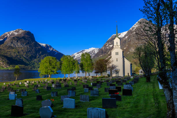 igreja de oppstryn e cemitério ao lado do lago oppstrynsvatnet e montanhas - cemetery hill - fotografias e filmes do acervo