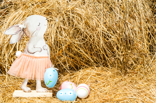 A pink rabbit and an egg in the middle of a meadow. Easter concept.