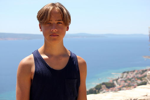 Teenager boy portrait by the sea in summer, Mediterranean Sea, Omis, Dalmatia, Croatia. Summer vacation background.