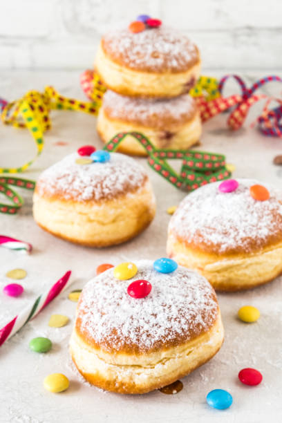 istock Carnival powdered sugar raised donuts with paper streamers, confetti and chocolate beans on white background, vertical 1460520265