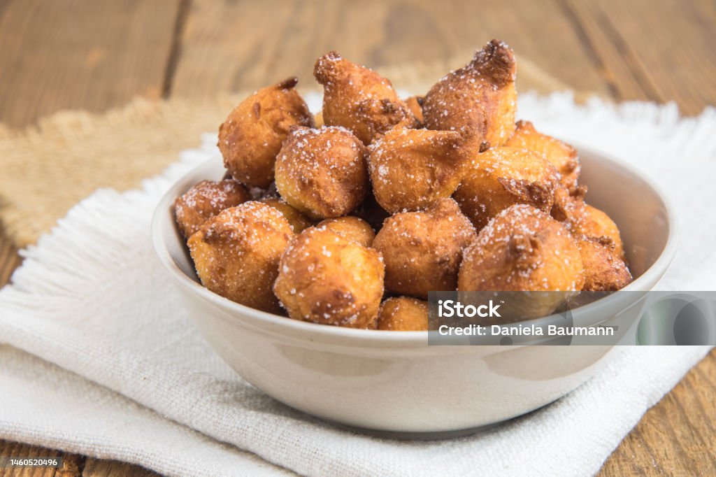 自家製カスタニョーレ素朴な木製のテーブルの上の白いボウルに砂糖を入れた典型的なイタリアのカーニバルフリッター おやつのストックフォトや画像