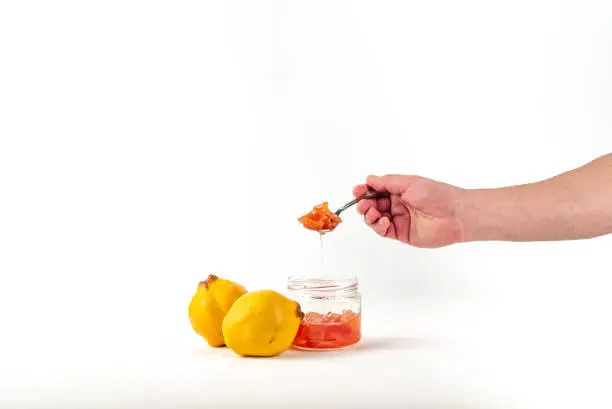 Photo of Sitting view man holding spoon Fresh ripe quince and jam on white background isolated.