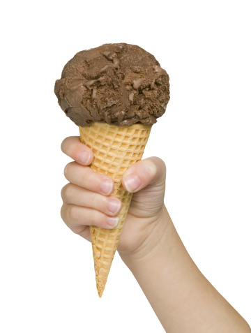 Child's hand holding chocolate hand dipped ice cream waffle cone