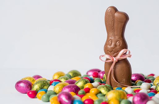 A beautiful postcard. Banner. The concept of a bright Easter holiday. Chocolate Easter eggs and a chocolate rabbit on a white isolated background. Sweets and sweets.