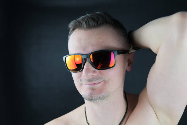 istock A young white man with reflective, red sun glasses is posing in the camera at a studio photo shoot. 1460525821